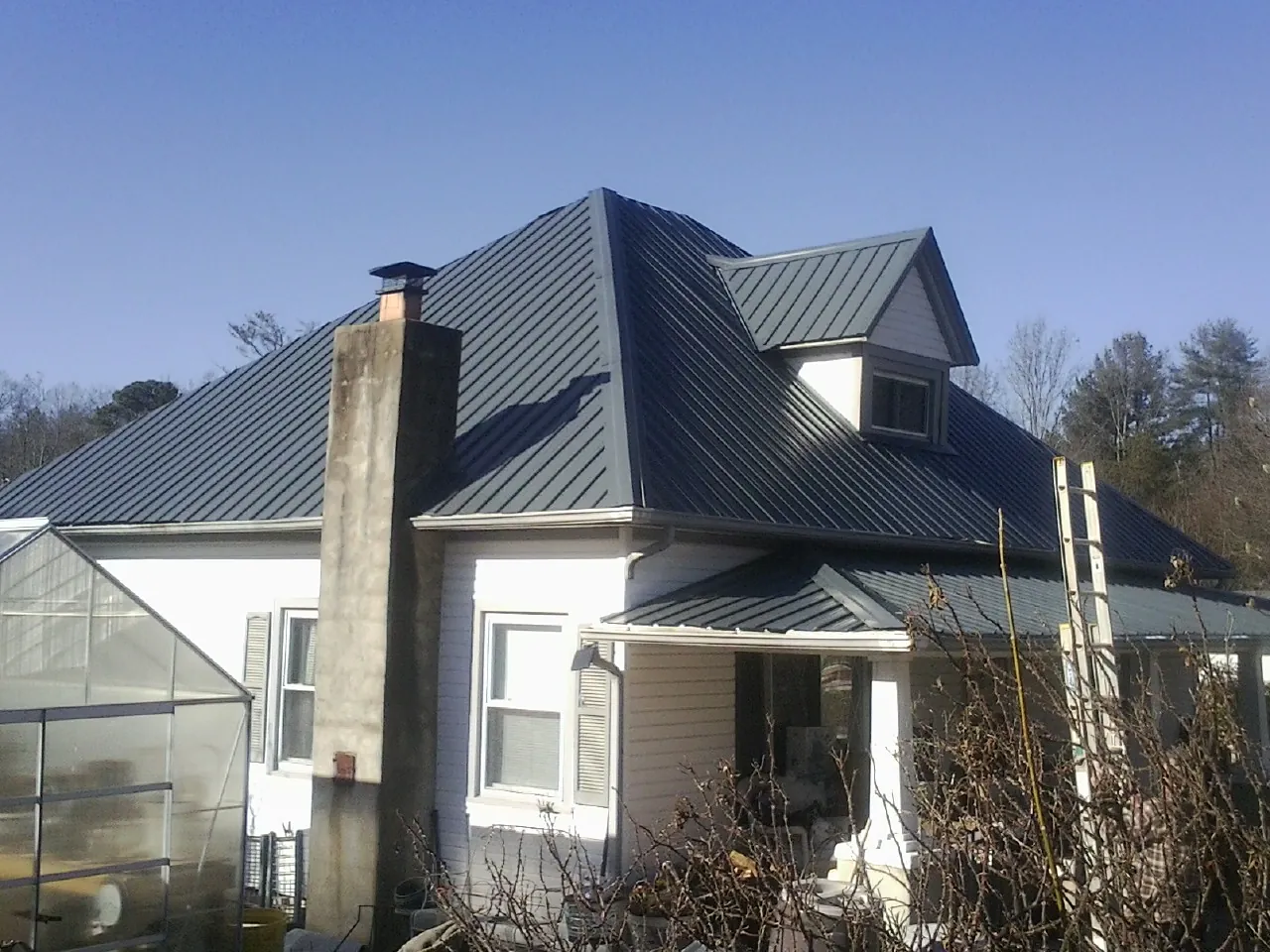 Dark blue standing seam metal roof on a white farmhouse with dormer — Slate & Tile Roof Repair by Roofing Brothers in Avondale